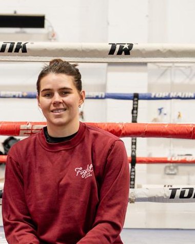 Savannah Marshall sitting on the edge of a boxing ring in a Fight Like a Girl sweatshirt